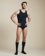 man wearing a navy cotton tank top, a brief, and socks. 